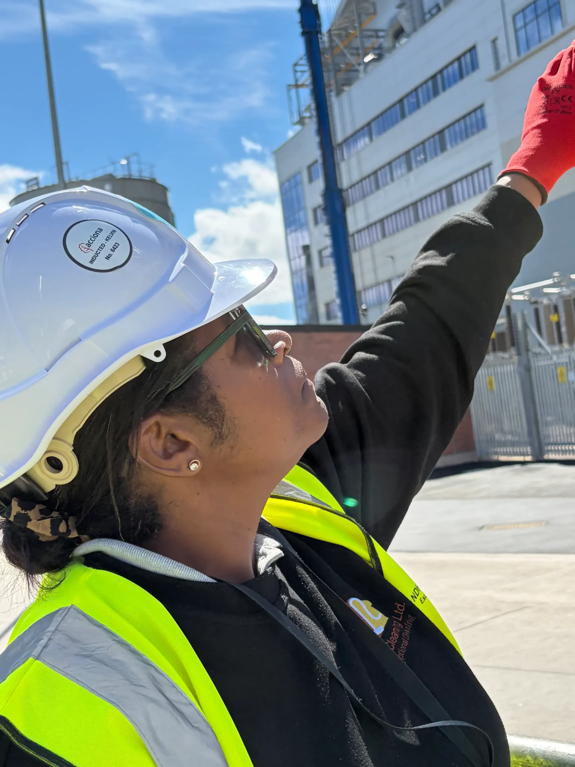 NDH Cleaning Ltd supervisor in hard hat and hi-vis surveying the exterior of a large industrial facility